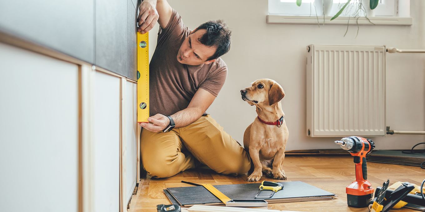 Man meet iets op en zijn hond zit naast hem en kijkt mee