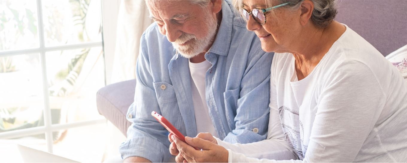 een bejaarde man en vrouw kijkend op de mobiele telefoon