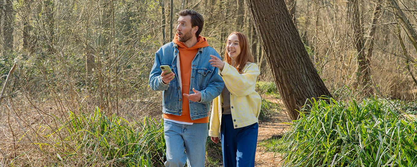 een man en vrouw in het bos met hun mobiel in hun handen op zoek naar de weg