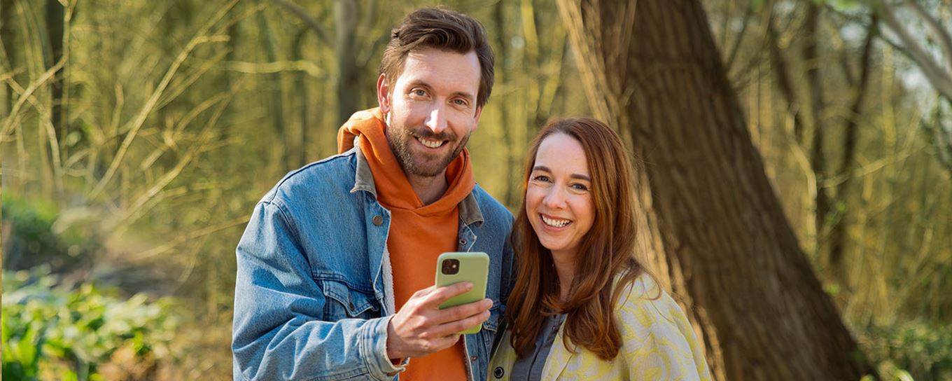 man en vrouw in het bos met een telefoon in hun handen