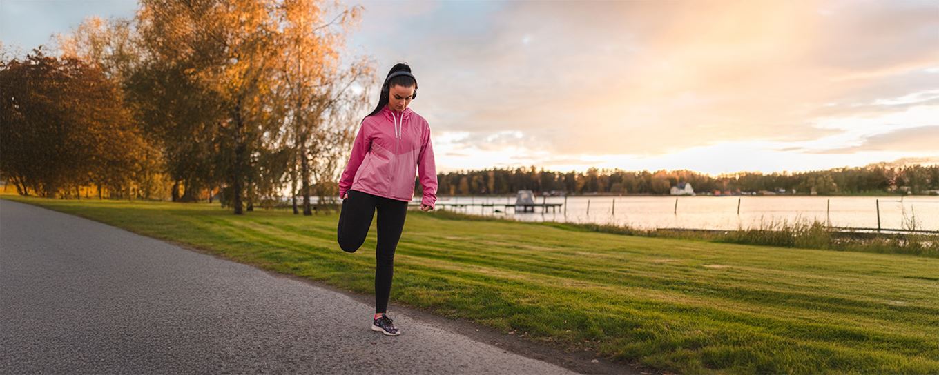 een jonge vrouw in een sportieve outfit doet rek en strek oefeningen op een wandelpad