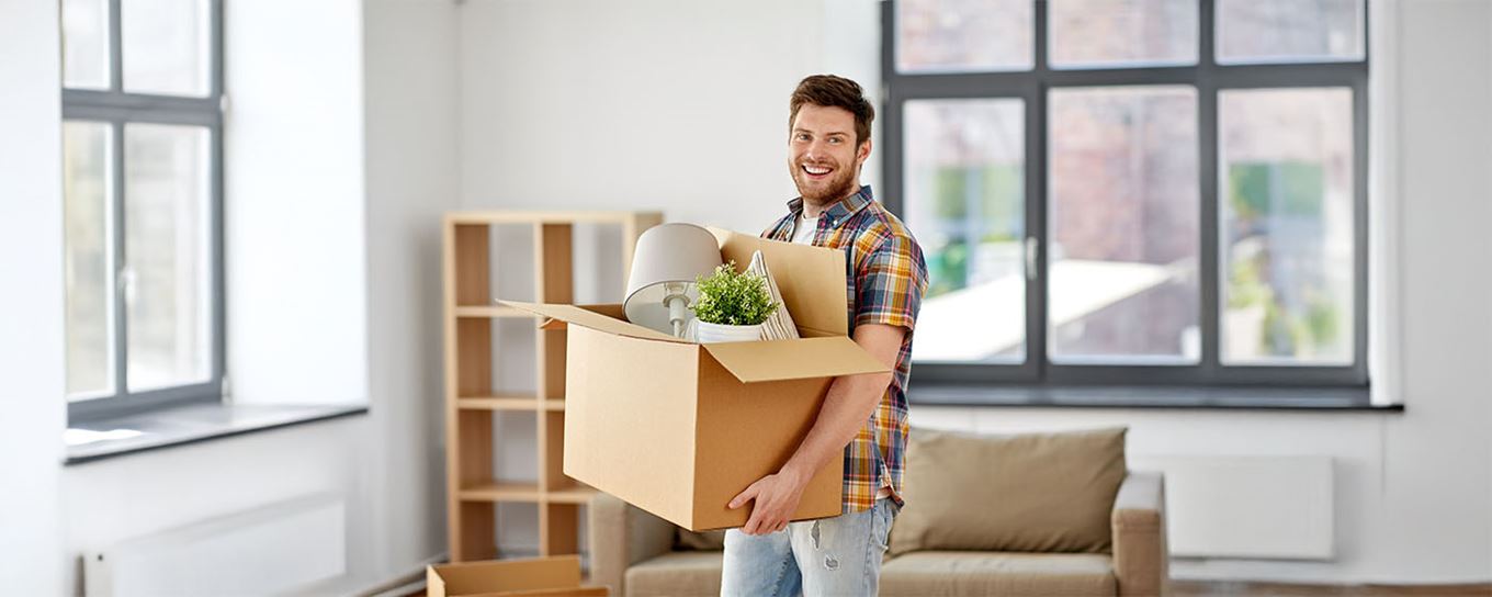 een jongeman houdt zijn verhuisdoos lachend vast