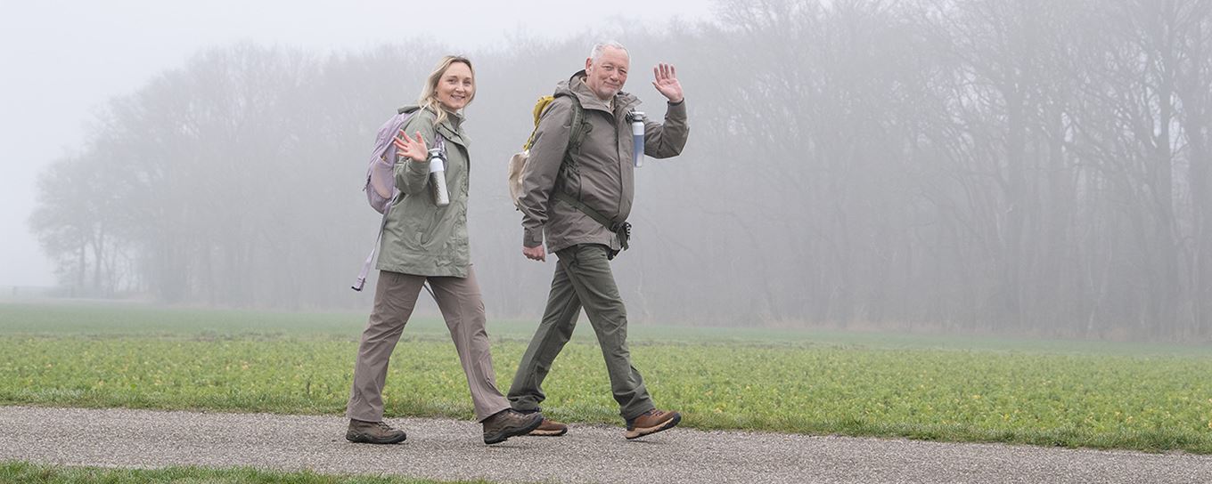 Een oudere man wandelt samen met zijn dochter buiten in de natuur