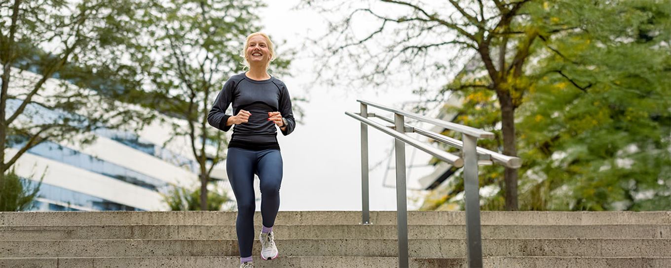 oudere vrouw loopt buiten van de trappen in een sportieve outfit