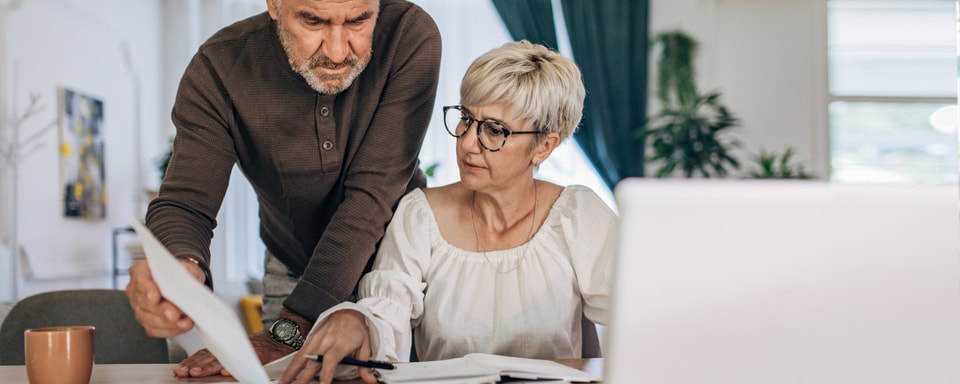 Echtpaar met papierwerk op bureau overleggen regelen verzekering online
