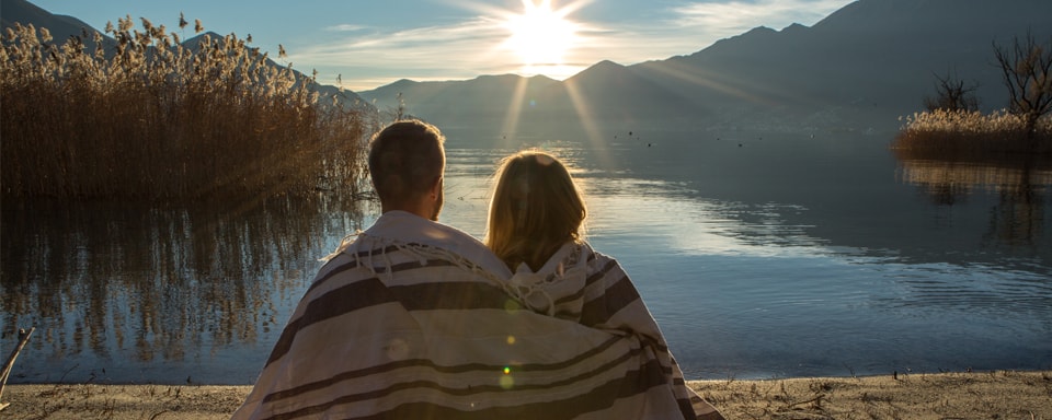 Stel kijkt naar zon die achter in het buitenland achter bergen ondergaat