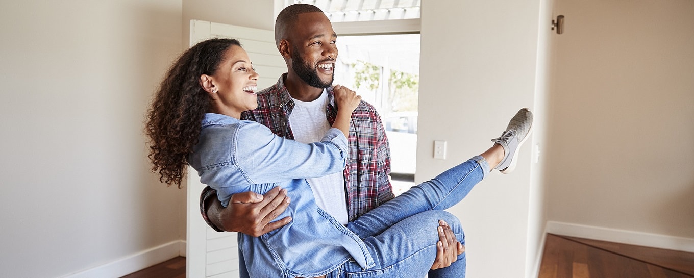Man draagt vrouw blij hun nieuwe huis binnen