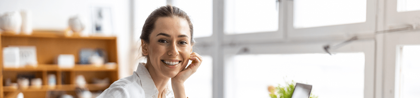 Vrolijke vrouw achter haar bureau kijkt in de camera | Doenpensioen | a.s.r.